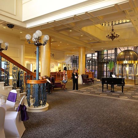 Hotel Stamford Grand Adelaide à Glenelg Intérieur photo The photo shows a luxurious interior of a hotel or a restaurant lobby. There is an elegant staircase with ornate railings leading to an upper level. The space features high ceilings with decorative chandeliers and ample natural light coming through l