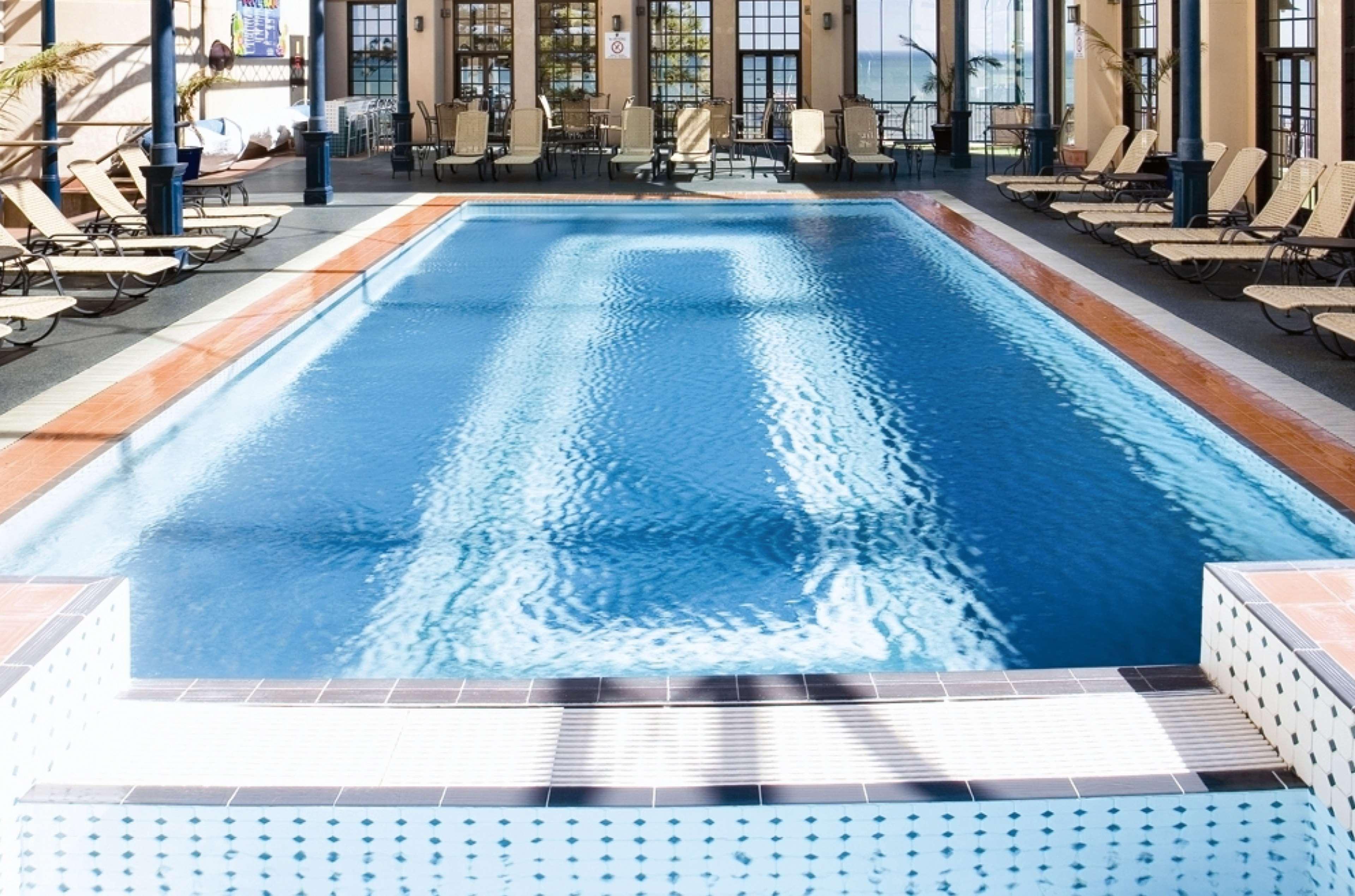 Hotel Stamford Grand Adelaide à Glenelg Extérieur photo The photo shows an indoor swimming pool with a pristine blue surface. The pool is surrounded by a tiled deck and has lounge chairs lined up along the sides. Large windows allow natural light to flood the area, creating a bright and inviting atmospher