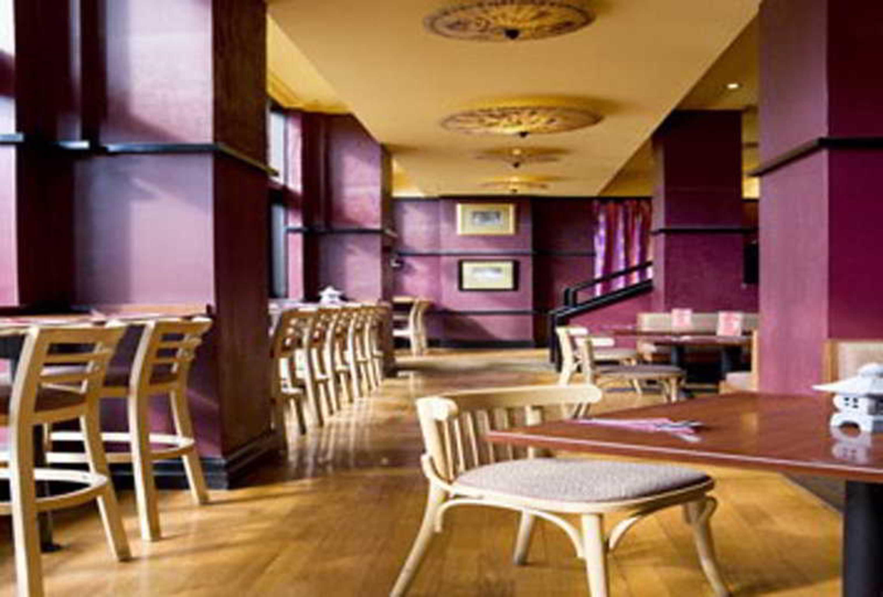 Hotel Stamford Grand Adelaide à Glenelg Extérieur photo The photo shows the interior of a restaurant. It features wooden flooring and a warm color palette, primarily using shades of burgundy and gold. There are several wooden chairs arranged around tables, with the seating area appearing spacious and invi