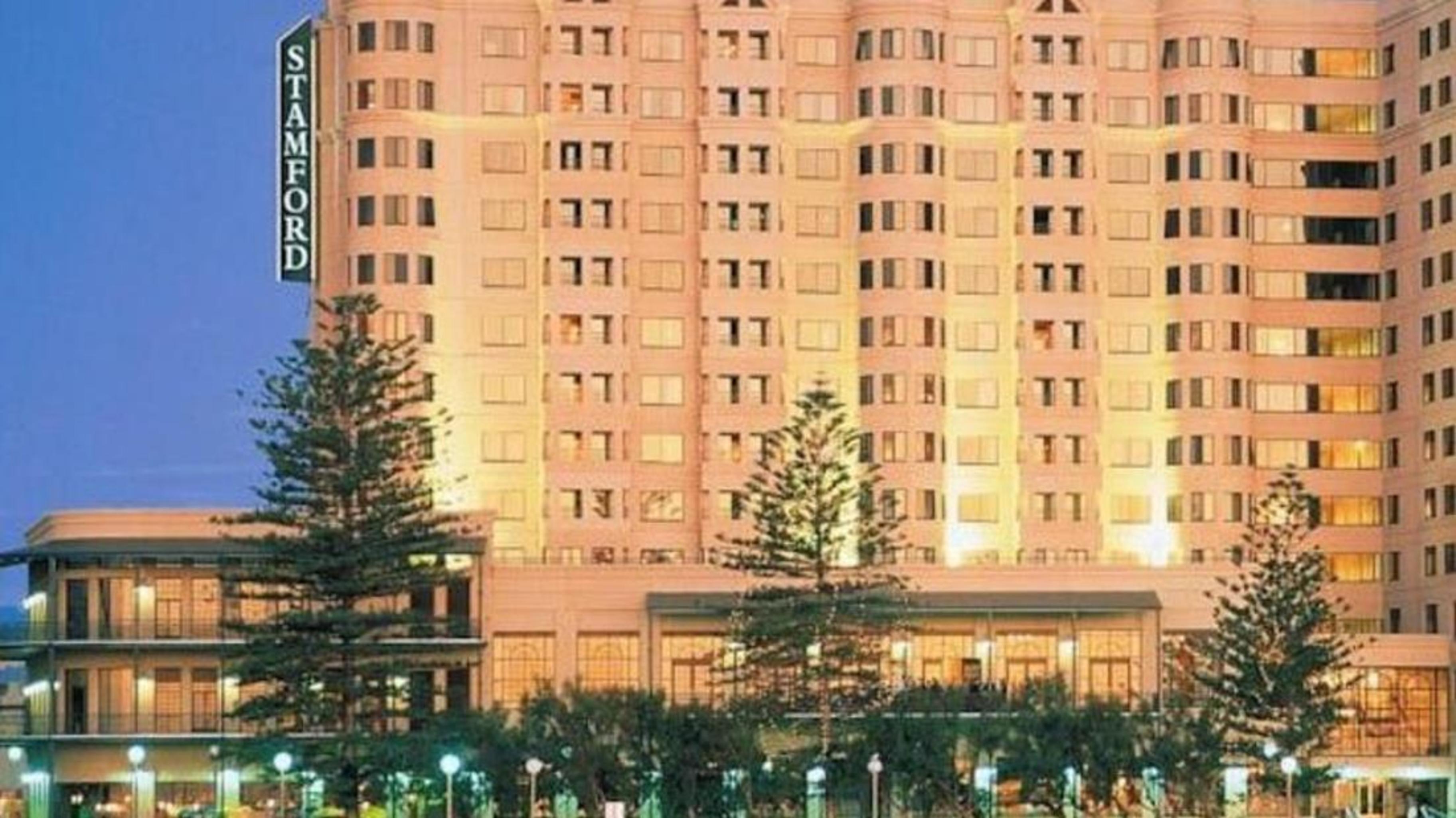 Hotel Stamford Grand Adelaide à Glenelg Extérieur photo The photo shows a tall, modern building illuminated at night, likely a hotel, with the name "Stamford" prominently displayed on its side. Surrounding the building are several palm trees and landscaped areas, suggesting a tropical or coastal location.