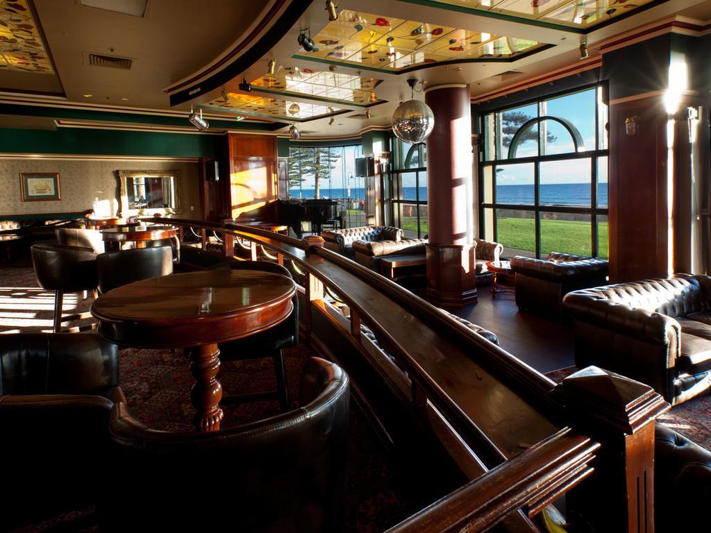 Hotel Stamford Grand Adelaide à Glenelg Extérieur photo The photo depicts a stylish and inviting interior of a lounge or bar. It features comfortable leather seating, wooden tables, and large windows that provide a view of the outdoors. The ceiling is adorned with decorative elements, and there’s a disco 